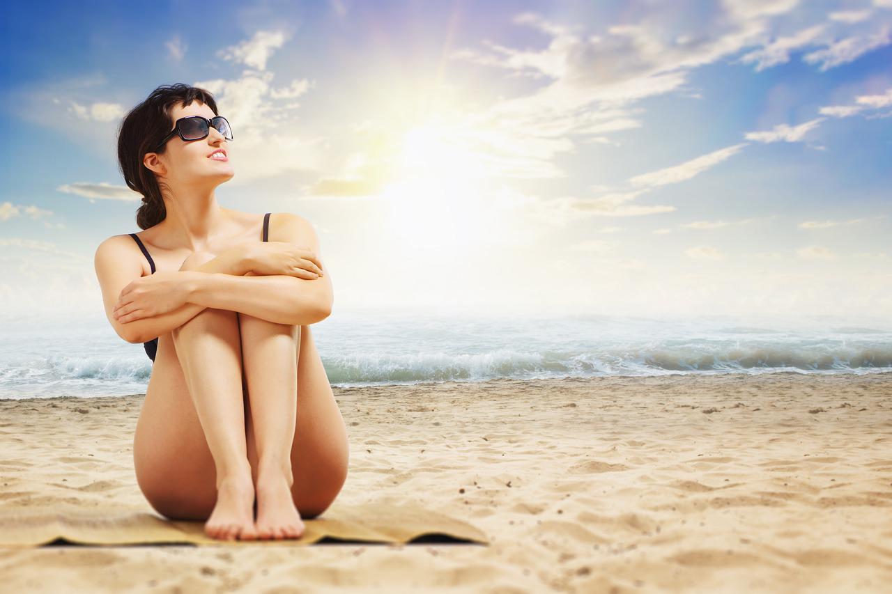 devojka sedi na suncu sa naocarima i drzi ruke preko kolena